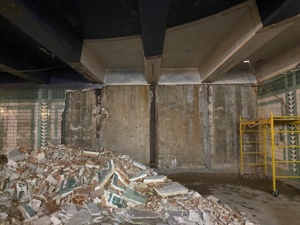 Existing tile and reinforced concrete wall are being demolished in preparation for the future staircase and escalator.